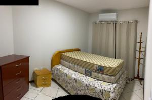 イタペマにあるApartamento Meia Praiaのベッドとドレッサーのある小さな寝室
