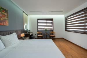 a bedroom with a bed and a desk and two chairs at Luxe Paradise Hotel Nguyen Khac Hieu in Hanoi