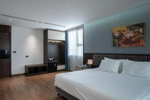 a bedroom with a white bed and a painting on the wall at Luxe Paradise Hotel Nguyen Khac Hieu in Hanoi