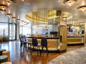 a bar in a restaurant with black stools at Mercure Hotel Freiburg am Münster in Freiburg im Breisgau