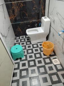a bathroom with a toilet with a checkered floor at Jay shree Kedar room in Ujjain