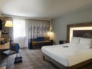 une chambre d'hôtel avec un grand lit et un canapé dans l'établissement Novotel Coventry, à Coventry