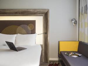 une chambre avec un lit avec un ordinateur portable dessus dans l'établissement Novotel Coventry, à Coventry 107 autres photos