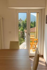 a dining room table with chairs and a view of a balcony at Casa Perla dei Laghi - Lake View, BBQ, WiFi 1Gb & AirCond in Porlezza
