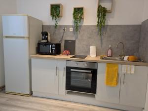 a kitchen with white cabinets and a refrigerator at Appartement RDC Soleil in La Flèche