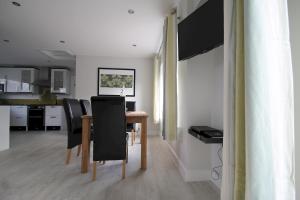 a dining room with a table and black chairs at Honeysuckle Cottage with Hot Tub Park Facilities in Milford on Sea