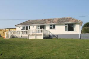 a white house with a porch and a yard at Honeysuckle Cottage with Hot Tub Park Facilities in Milford on Sea