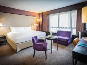 a hotel room with a bed and two purple chairs at Sofitel Strasbourg Grande Ile in Strasbourg