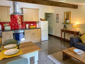 a kitchen and living room with a table and a couch at Chestnut Cottage - 27636 in Darenth