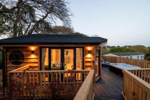 une petite cabine avec une terrasse et un bain à remous dans l'établissement The Spinney Treehouse Park Facilities, à Milford on Sea