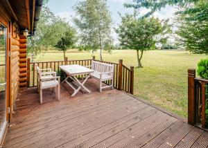 a wooden deck with two chairs and a table at Laxfield Lodges in Laxfield +5 photos