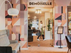 a woman walking into a store with a sign on the wall at Mercure Paris CDG Airport & Convention in Roissy-en-France