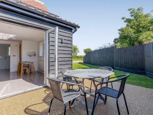 un patio con tavolo, sedie e una recinzione di Blackberry Cottage a Stowmarket