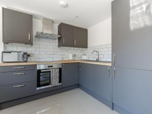 una cucina con armadi blu e forno a microonde di Blackberry Cottage a Stowmarket Altre 4 foto