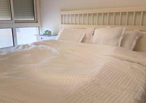 a large white bed with white sheets and pillows at High Altitude Makkah - Aziziya Spacious Flat in Makkah