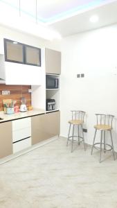 a kitchen with white cabinets and two stools at MM Luxury 3 bedroom Duplex Terrance in Aja