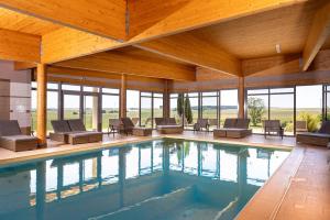 a pool in a house with chairs and windows at LE VAL MORET Hôtel Restaurant et Spa in Magnant