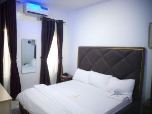 a hotel room with a bed with white sheets at The Cartwright Suite and Lounge in Warri