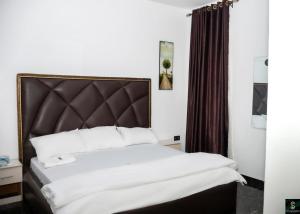 a bedroom with a large bed with a brown headboard at The Cartwright Suite and Lounge in Warri