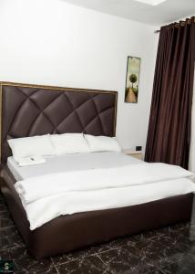 a bedroom with a large bed with a brown headboard at The Cartwright Suite and Lounge in Warri