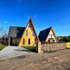a yellow house with a black roof and a fence at Challet in Cheia