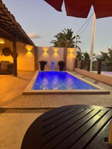 einen Pool mit blauem Wasser vor einem Haus in der Unterkunft Casa de Praia - Aracaju - Jatobá in Barra dos Coqueiros