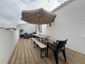 eine Terrasse mit Tisch und Stühlen und einem Sonnenschirm in der Unterkunft Maison neuve proche plage, 3 chambres, 6 couchages à Saint-Denis d'Oléron - FR-1-246A-374 in La Michelière