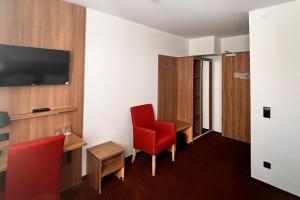 a hotel room with a red chair and a tv at Novum Hotel Bruy in Stuttgart