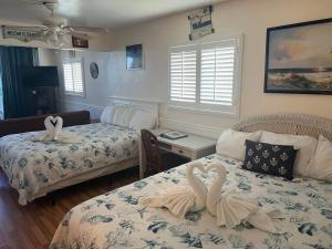 two swans are sitting on two beds in a room at Waterfront 2 Queens Free Parking in Clearwater Beach +22 photos