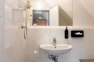 a white bathroom with a sink and a mirror at Novum Hotel Bruy in Stuttgart +69 photos