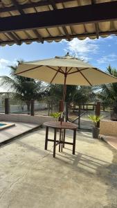 einen Picknicktisch mit Sonnenschirm auf einer Terrasse in der Unterkunft Casa de Praia - Aracaju - Jatobá in Barra dos Coqueiros
