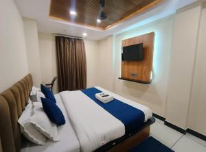 a bedroom with a bed with a tv on the wall at Hotel Shree Anadi Palace in Ujjain
