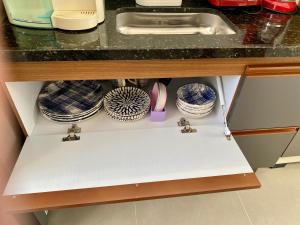 a kitchen cabinet with plates and dishes in it at Elegância Praia da Sereia in Vila Velha +28 photos