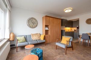 a living room with a couch and chairs and a kitchen at Cozee in Ostend