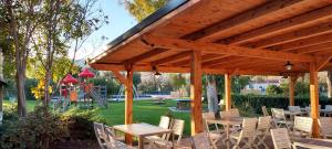 a wooden pavilion with tables and chairs and a playground at Sarzana- Mobilhome 5 persone Pool and Garden in Sarzana +13 photos