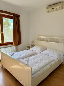 a white bed in a bedroom with a window at Beach Apartman by HelloBalatonlelle in Balatonlelle