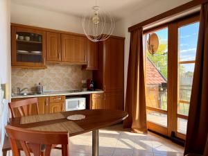 a kitchen with wooden cabinets and a table and a window at Beach Apartman by HelloBalatonlelle in Balatonlelle