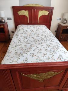 a bed with a wooden frame with a floral bedspread at Luna in La Coquille +1 photo