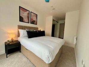 a bedroom with a large white bed and a night stand at Luxury 2 bed Apt Near Ascot & Windsor in Bracknell