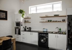 a kitchen with white cabinets and a washing machine at 1 bedroom cottage south of Cape Town in Marina Da Gama