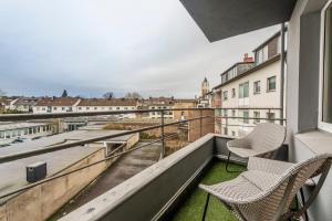 a balcony with two chairs and a view of the city at Klassen Stay - Design Apartments direkt am HBF Aachen in Aachen