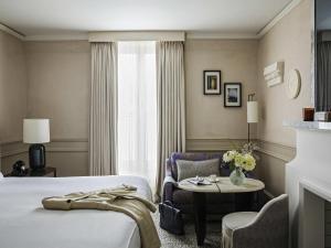 a hotel room with a bed and a table at Sofitel Le Scribe Paris Opera in Paris +224 photos