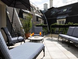 een terras met stoelen, een tafel en een parasol bij Sofitel Le Scribe Paris Opera in Parijs