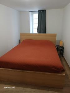a bedroom with a bed with a red bedspread at Bel appartement au centre du vieux Nyons en Drôme Provençale in Nyons
