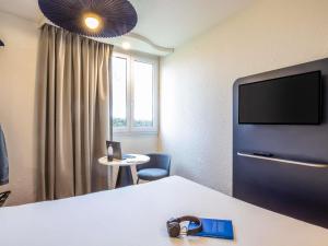a room with a bed and a tv and a chair at ibis Chalons en Champagne in Châlons-en-Champagne