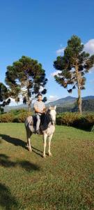 a person riding a white horse in a field at Refúgio Rio do Boi in Praia Grande