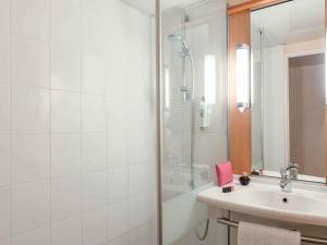 a white bathroom with a shower and a sink at ibis Paris la Défense Esplanade in Courbevoie +40 photos