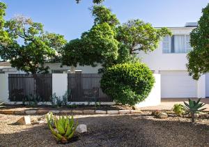 a white house with a fence and a cactus at 1 bedroom cottage south of Cape Town in Marina Da Gama