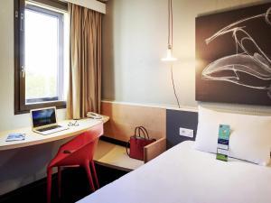 une chambre d'hôtel avec un lit et un bureau avec un ordinateur portable dans l'établissement ibis Lyon Gerland Musée des Confluences, à Lyon