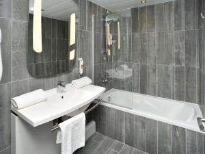 a bathroom with a sink and a tub and a mirror at ibis Lyon Centre in Lyon +51 photos